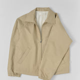 Top-shot photograph of a made in japan Beige water-repellet jacket with a YKK zipper on a light gray background.
Artisanal approach, Designed in Switzerland , Made in Japan
